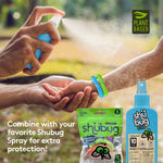 Close-up of hands spraying mist onto a child's wrist wearing colorful coil bracelets, with Shubug pouch and spray bottle shown.