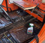 Open vehicle interior showing bare metal floorboards with a Spray Nine bottle placed on the floor