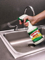 Hand squeezing trigger of a Spray Nine bottle to spray cleaner over a stainless steel sink and faucet