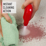 Close-up of red spray nozzle applying cleaner to a carpet stain while a hand holds a green towel, text reads instant cleaning action
