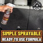 Hand spraying Chemical Guys leather-scent odor eliminator into a vehicle cargo area with visible spray mist and product logo