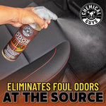Close-up of hand spraying Chemical Guys leather-scent odor eliminator over a car seat with mist visible