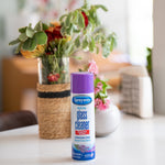 Sprayway glass cleaner can with purple cap placed on a table in a home setting with blurred floral arrangement behind it