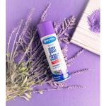 Single Sprayway glass cleaner can lying on a purple background among sprigs of dried lavender and a wooden board.