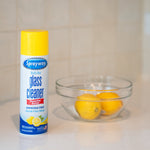 Sprayway glass cleaner can with yellow cap beside a clear bowl of lemons on a tiled countertop