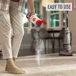 Person sprinkling powder from a Hoover container onto carpet while an upright vacuum stands in the room