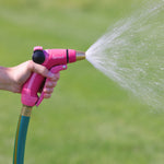 Hand-held pink Sprout front-trigger nozzle spraying water in a wide fan pattern over a lawn