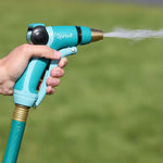 Hand gripping a Sprout hose nozzle spraying a narrow stream of water outdoors over grass