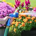 Close view of a blue Sprout hose nozzle in hand spraying a steady fan of water at bright garden flowers