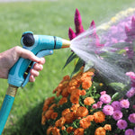 Sprout adjustable metal nozzle spraying water onto colorful garden flowers from close range
