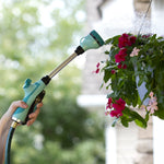 Hand-held Sprout gooseberry green watering wand watering hanging pink flowers with a misty spray, outdoor scene