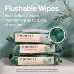 Three stacked Honest flushable wipes packs in green tropical-leaf design with product text and a magnified pattern inset.