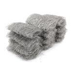 Stack of loose gray steel wool pads arranged on a white background showing fibrous texture and shape