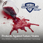 Spilled red liquid on carpet beside a StainProtect shield logo and text about protecting against future stains