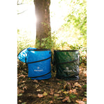 Two Stansport collapsible bins, one blue and one green, standing side by side on the ground beneath a tree.