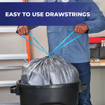 Hands pulling bright blue drawstrings closed on a gray trash bag inside a black trash can with Hefty branding banner