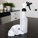 Translucent spray bottle on a kitchen countertop next to a white cleaning cloth