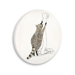 Circular wall plaque showing a raccoon reaching for a roll of toilet paper illustration
