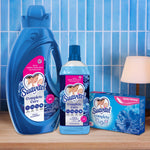 Styled product scene with large Suavitel bottle, smaller bottle and box of sheets on a wooden surface against blue tile
