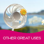 Yellow sun-shaped air freshener attached to a tabletop fan with blurred seaside view