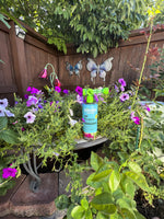Sunday WonderFert All Purpose bottle placed among pink and purple petunias on a garden table with wood fence background