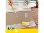Lifestyle image of a Swiffer 360° Dusters extender being used to dust along a baseboard near a planter