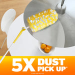 Lifestyle image of yellow Swiffer duster reaching a hanging lamp above a table with bowl of oranges