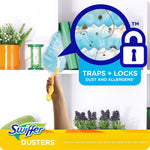 Swiffer duster being used to clean a shelf with inset magnified graphic showing trapped dust and a 'Traps + Locks' badge.