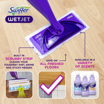 Close-up of a purple Swiffer WetJet mop head on a wood floor with icons showing scrubby strip and floor compatibility.