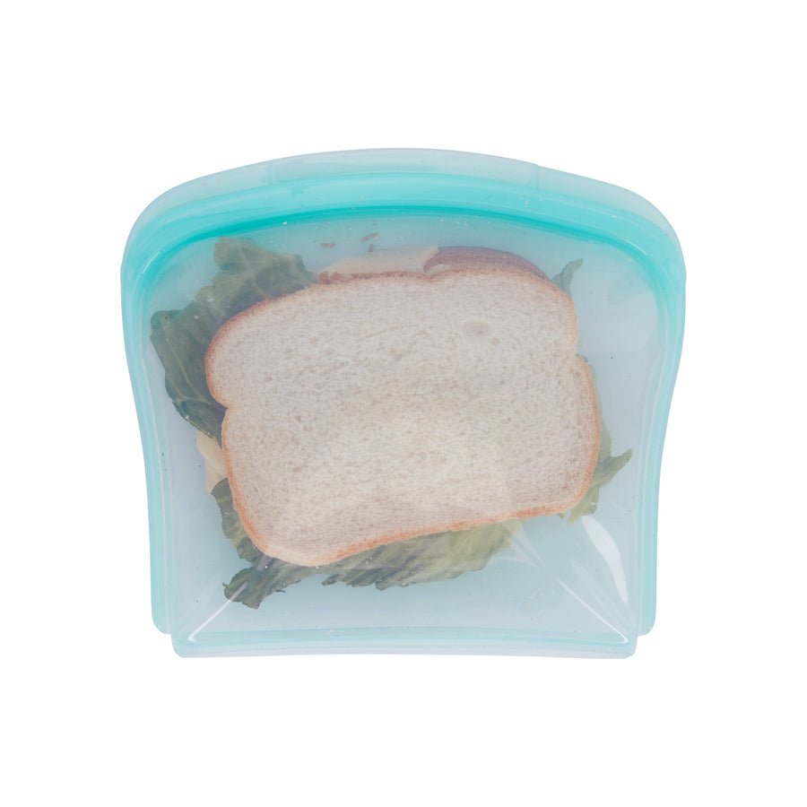 Top-down view of a teal reusable silicone sandwich bag holding a lettuce and cheese sandwich on white background