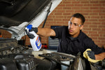 Worker wearing safety glasses using a GUNK spray bottle to spray a car engine bay