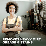 Smiling technician in safety glasses holding wrenches in a workshop with overlay text about removing heavy dirt and grease