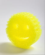 Yellow Scrub Daddy smiley-face sponge photographed upright with textured pores visible on a neutral background.