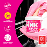 Hand in pink glove holding a small tub of The Pink Stuff with icons and text highlighting cleaning benefits.