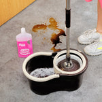 Mop bucket and mop with a small pink bottle of The Pink Stuff on the floor beside a stain
