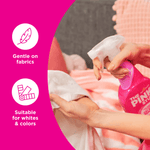 Lifestyle shot of a person spraying The Pink Stuff bottle onto fabric, with icons for "Gentle on fabrics" and "Suitable for whites & colors"