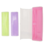 Three pastel toothbrush travel cases, two closed (lime and lavender) and one open showing a pink molded interior, on white background.