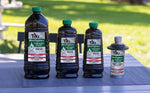 Three sizes of dark TIKI BiteFighter torch fuel bottles and a small TIKI disposable canister displayed on a picnic table outdoors
