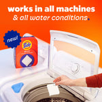Tide evo packaging beside a top-load washing machine with a hand dropping a white detergent tile into the drum