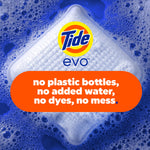 Close-up of a Tide evo detergent tile partially submerged in blue soapy water with bold eco messaging overlay