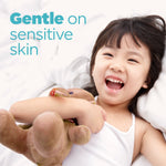 Laughing child holding a stuffed animal on a bed with overlay text ‘Gentle on sensitive skin’