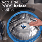 Hand placing a Tide Power Pod into the drum of a front-load washing machine with instructional text about adding pods before clothes.