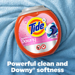 Tide Power PODS Downy container placed on a textured blue fabric background, highlighting the pink label.