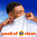 Person smelling a white shirt with text ‘smell of Tide clean’ and Tide logo over a blue sky background