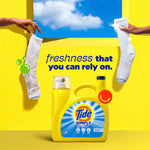 Tide Simply detergent bottle on a yellow ledge with two hands holding socks and tagline ‘freshness that you can rely on’