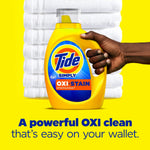 Hand holding a yellow Tide Simply OXI+Stain detergent bottle against stacked white towels and a bright yellow backdrop