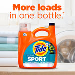 Tide Ultra Sport bottle on a laundry room counter with stacked linens and text 'More loads in one bottle.'