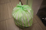 Tied green-and-white striped trash bag filled and tied closed on tiled floor