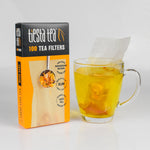 Tiesta Tea 100 tea filters box next to a clear mug of steeping tea with a filter pouch partially submerged