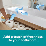 Bathroom drawer stocked with white toilet paper rolls and floating fresh-linen scent ribbons